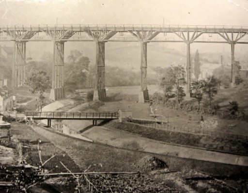 View of the original wooden viaduct, Stambermill Viaduct, Stourbridge, c. 1865. Stambermill Viaduct carried the Oxford, Worcester and Wolverhampton Railway over the River Stour from Stourbridge to Dudley. This wooden viaduct was replaced in 1881 by a brick viaduct, built by the Great Western Railway. The original stone piers for the wooden viaduct were designed by Isambard Kingdom Brunel. From Streetlifers of Stourbridge and All Surrounding Areas Facebook Group April 2025. An identical picture can be found in Dudley Archives at Ref: p/6